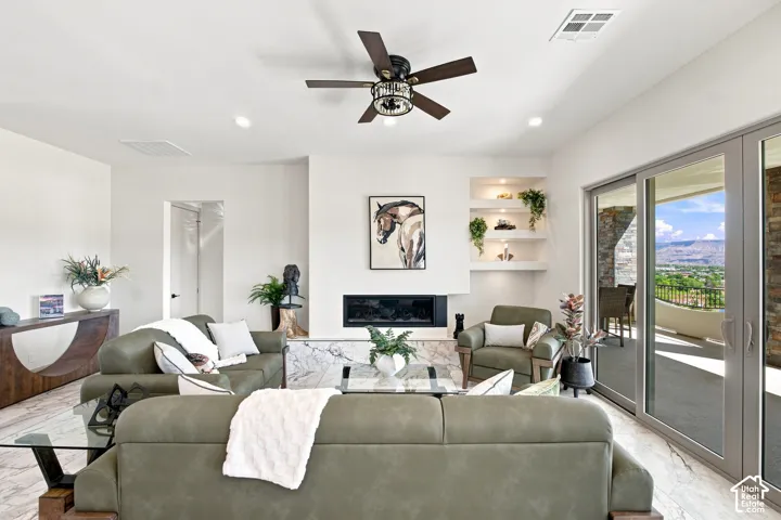 Living area featuring white walls, recessed lighting, a ceiling fan, and a built-in fireplace with a stone surround