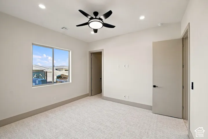 Recessed lighting, ceiling fan, expansive window, neutral wall paint, and textured carpeting