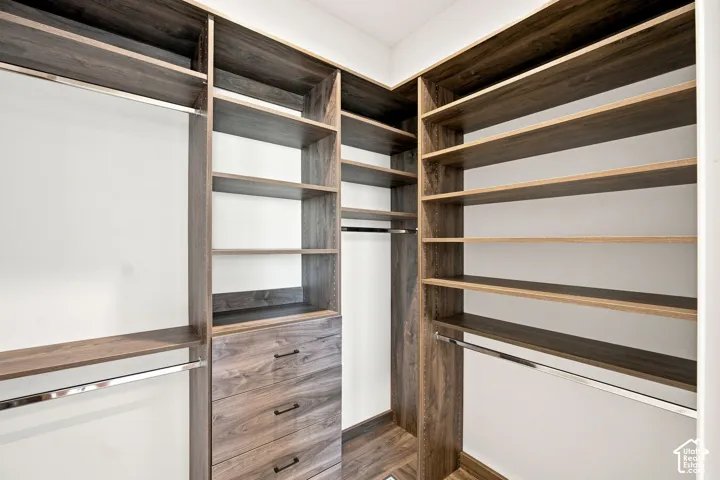 Built-in closet system with wood-finish shelving, integrated drawers, and chrome hanging rods