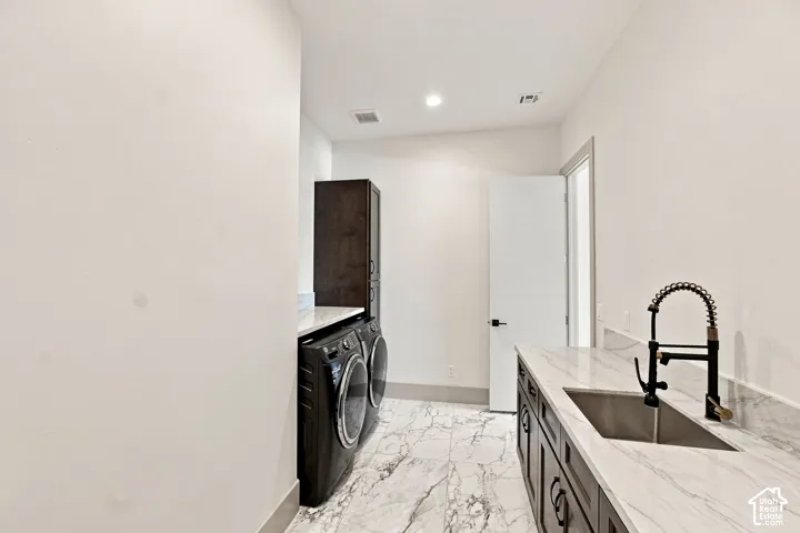 Laundry room featuring marble-look tile flooring, white countertops, built-in cabinetry, an under-mount sink, and a black pull-down faucet