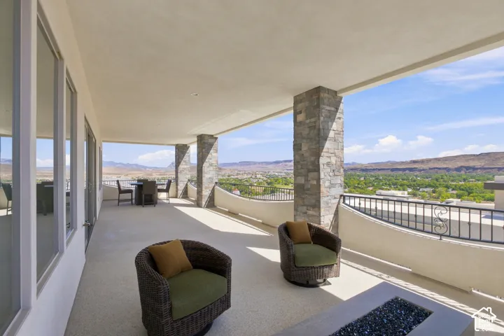 Expansive covered patio with stone-clad architectural pillars, concrete flooring, and a built-in fire pit