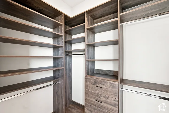 Custom closet system featuring wood-finish shelving, built-in drawers, and chrome hanging rods