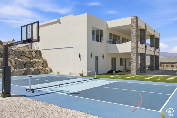 Modern exterior with multiple balconies, stone-clad columns, and a multi-sport court