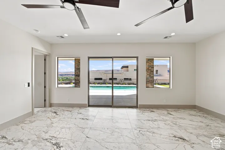 Marble-look tile flooring, two ceiling fans, recessed lighting, and a sliding glass door opening to an outdoor pool