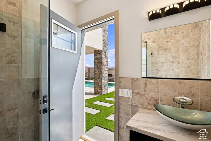 Shower with glass enclosure, stone-finish tile, and a vanity with a vessel sink