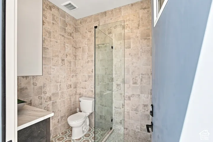 Glass-enclosed shower, floor-to-ceiling tile, patterned floor tile, vanity with countertop, wall-mounted cabinet