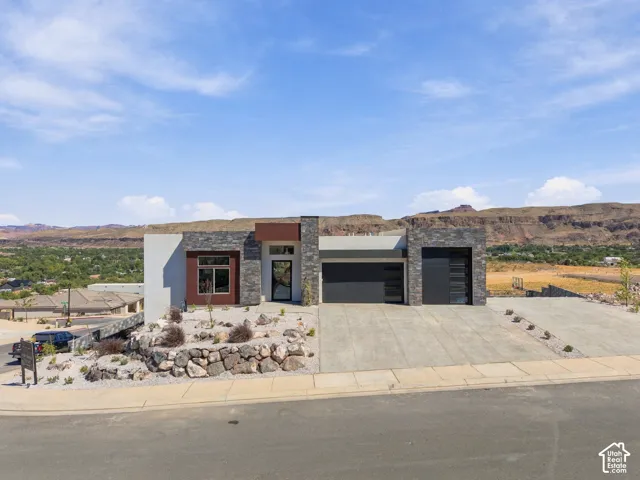 Modern exterior featuring stone and stucco finishes, a multi-panel garage door, and desert-inspired landscaping