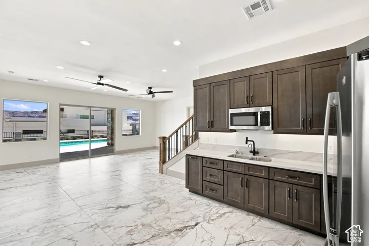 Marble-look tile flooring, built-in wet bar with dark wood cabinetry, stainless steel microwave, and integrated sink