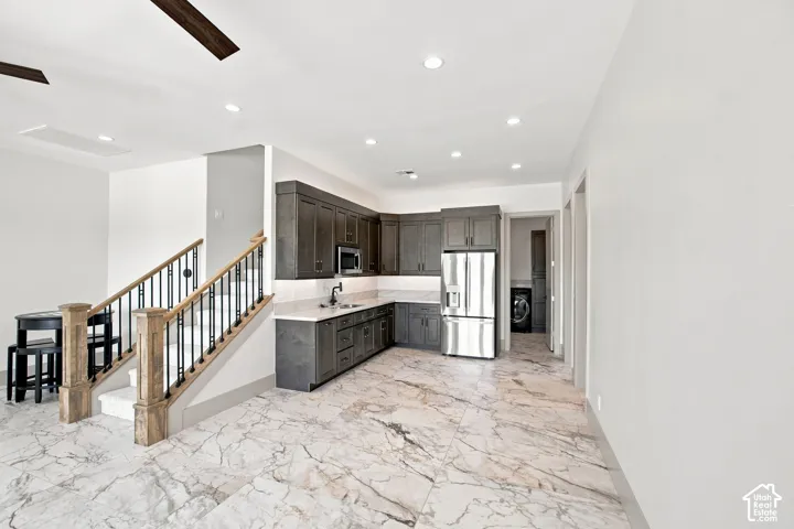 Spacious open-concept area featuring a built-in wet bar with dark wood cabinetry, stainless steel appliances, and a polished countertop