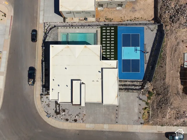 Outdoor swimming pool, paved court with basketball hoop, artificial turf, perimeter fencing, and concrete driveway