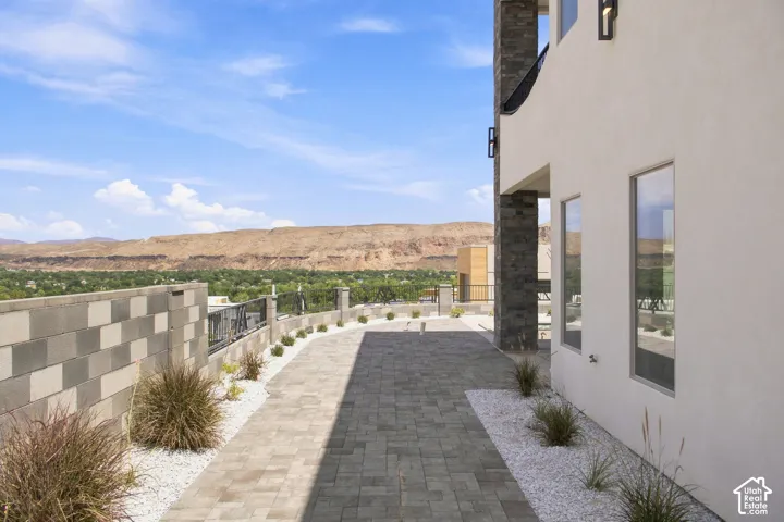 Paved patio with decorative stone accents, bordered by a block wall and modern railing