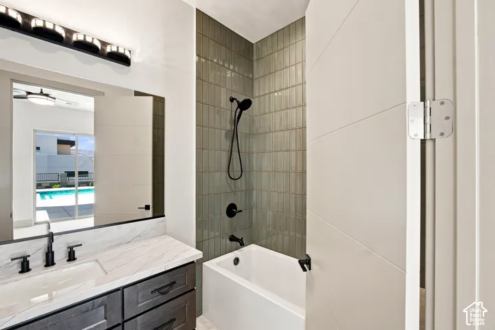 Bathroom with a deep soaking tub, matte black shower fixtures, vanity with a white countertop, and a large wall mirror