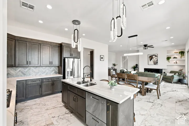 Open-concept kitchen featuring an island with dual sinks, dark cabinetry, and white countertops