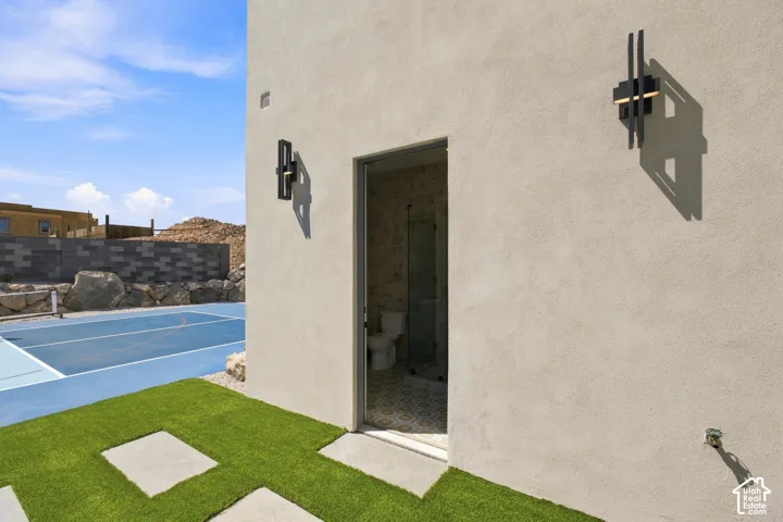 Exterior wall with modern sconce lighting and an open doorway revealing interior bathroom space