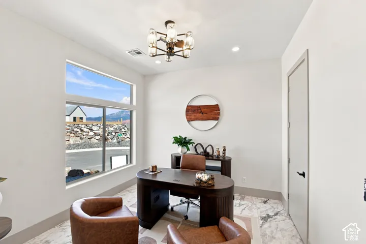 Recessed lighting and a decorative chandelier illuminate this room with a large picture window and transom window