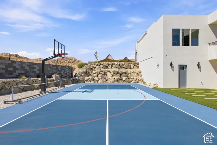 Multi-sport court with a basketball hoop and net, artificial turf, and a stucco exterior