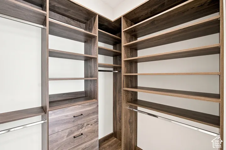 Custom closet system featuring wood-finish shelving, integrated drawers, and chrome hanging rods