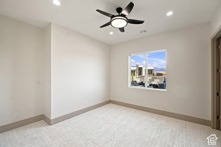 Recessed ceiling lighting, ceiling fan with integrated light, single window with white frame, patterned carpet flooring, and a paneled door with dark hardware