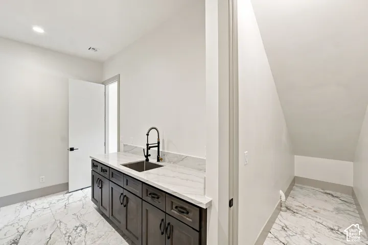 White marble-look flooring, dark wood-finish cabinetry, and a stainless steel sink with a black faucet