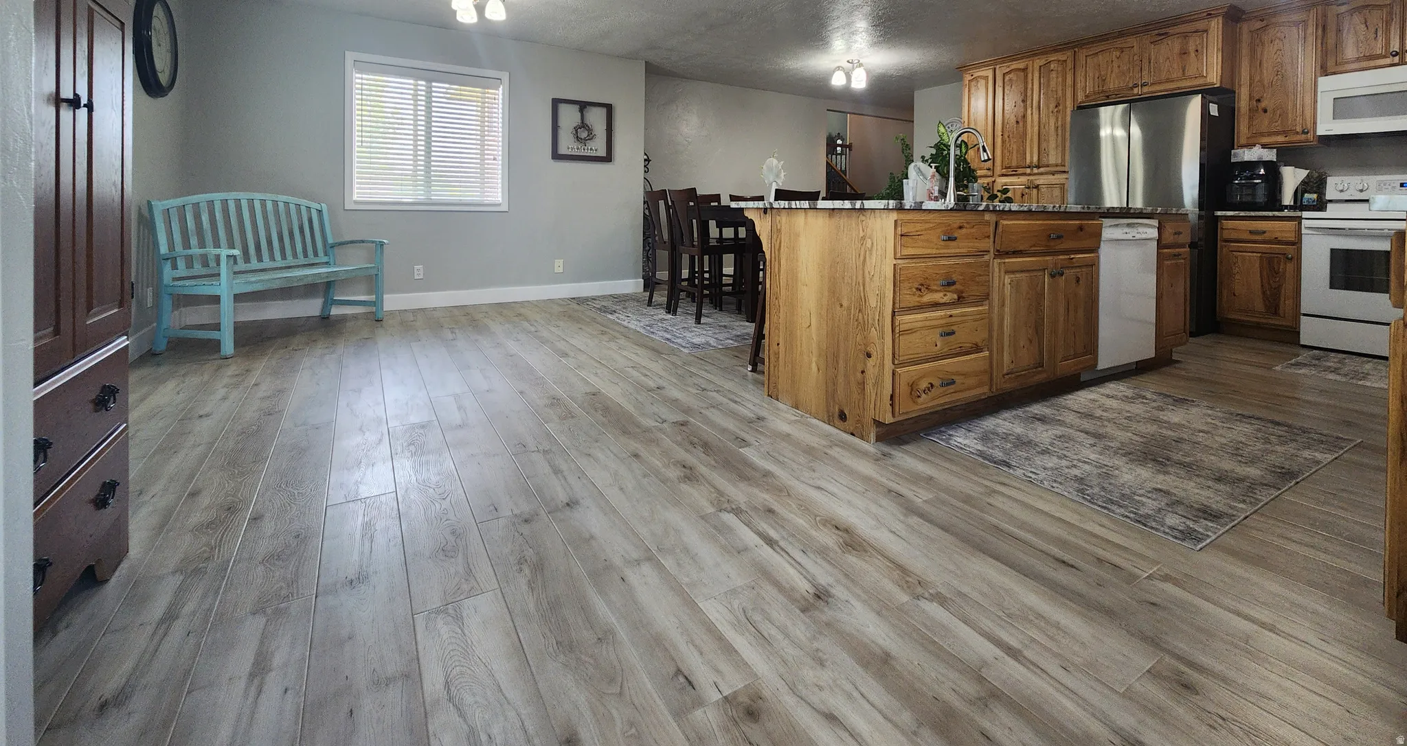 Spacious open-concept area featuring light wood-finish flooring throughout kitchen and dining room.