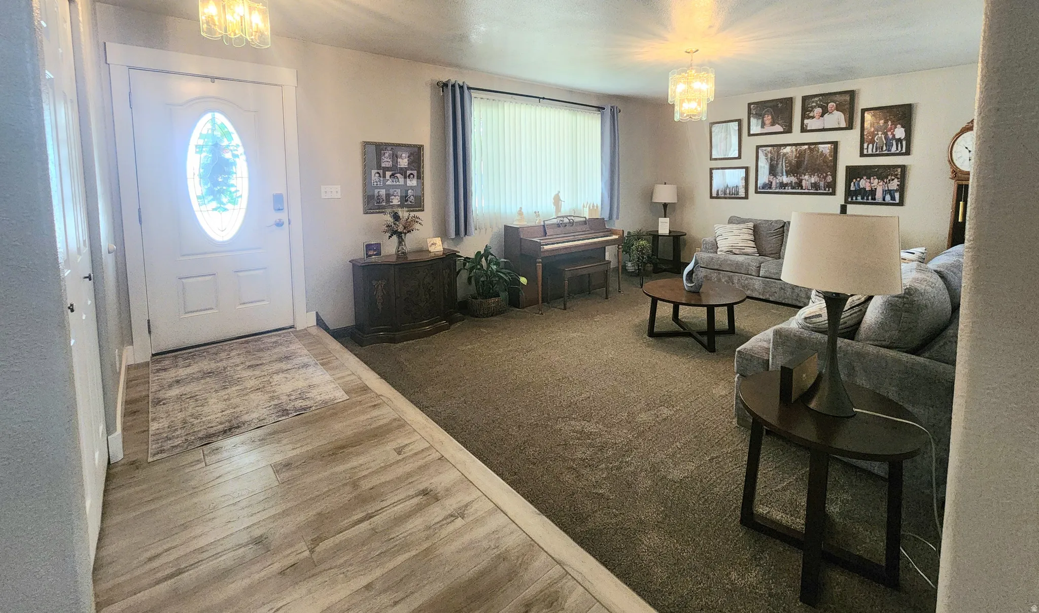 Welcoming entryway with light wood-finish flooring, a white oval-paneled door, and spacious formal living room.