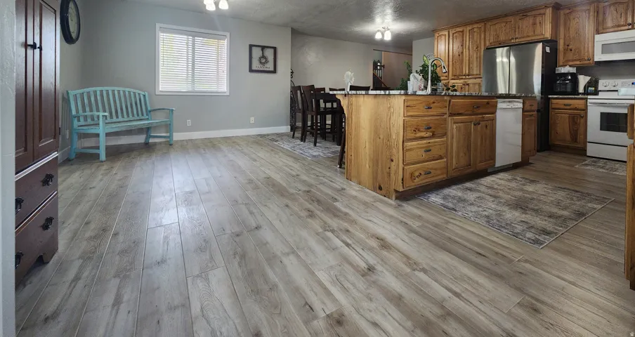 Spacious open-concept area featuring light wood-finish flooring throughout kitchen and dining room.
