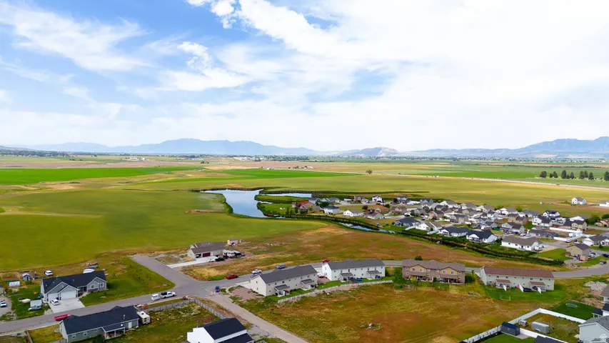 Expansive landscape featuring distant mountains, green fields, a winding waterway, and residential properties