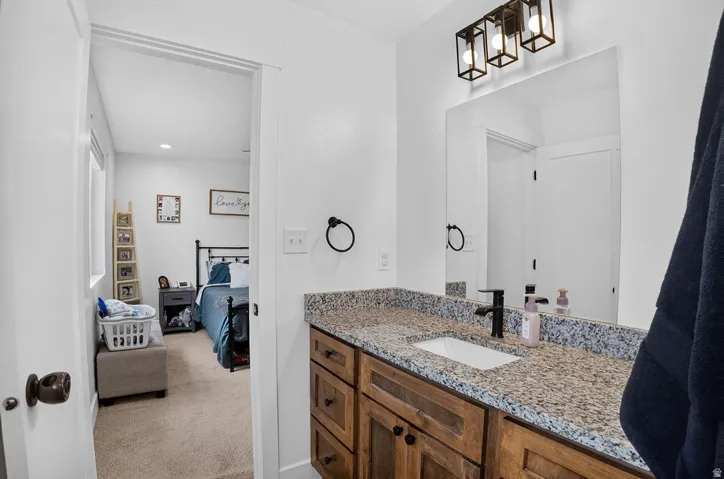 Bathroom vanity featuring a granite countertop, undermount sink, and matte black faucet