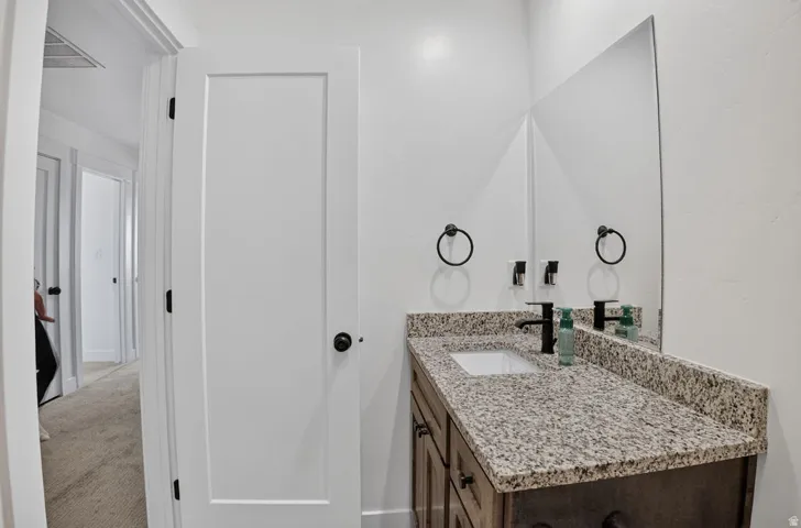 Vanity featuring a stone countertop, an undermount sink, and a matte black faucet
