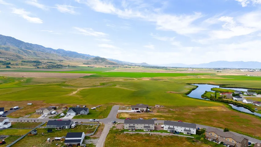 Expansive landscape featuring distant mountains, verdant fields, a winding waterway, and residential properties