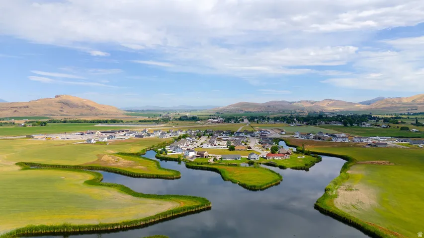 Aerial perspective showcasing a community situated around a body of water, with surrounding green fields and distant mountains