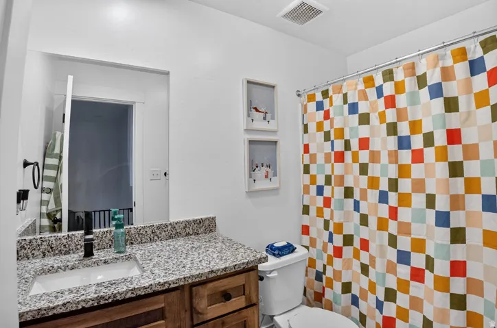 Bathroom featuring a light-toned countertop, sink with a dark-finish faucet, and wood-finish vanity cabinetry