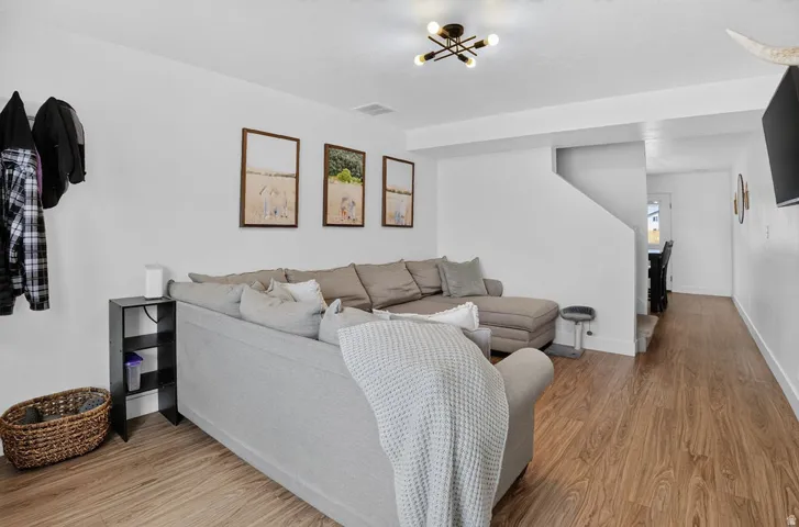 Open-concept living area featuring wood-finish flooring, white walls, and a contemporary multi-bulb ceiling fixture