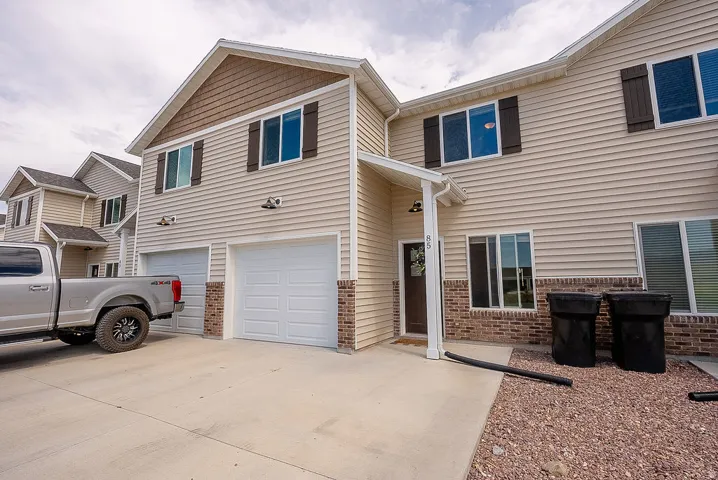Exterior featuring beige siding, brick accents, and a dual garage