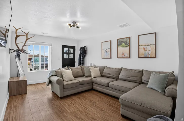 Living area featuring wood-finish flooring, white walls, and a contemporary ceiling light fixture