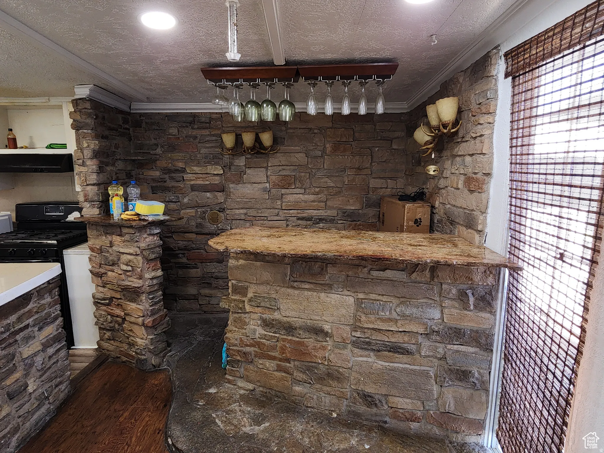 Stone-clad wet bar featuring a natural stone countertop and a built-in wine glass rack