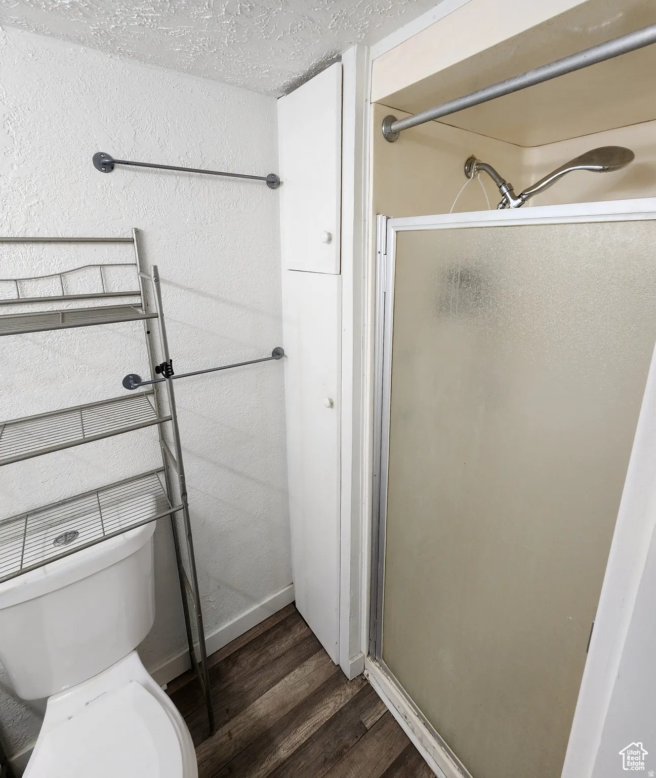 Compact bathroom featuring a walk-in shower with a frosted glass enclosure
