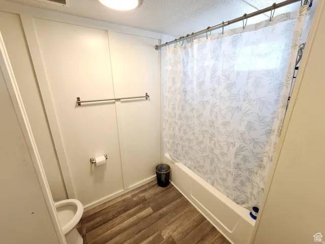 Bathroom featuring a white bathtub, wood-finish flooring, and white paneled walls