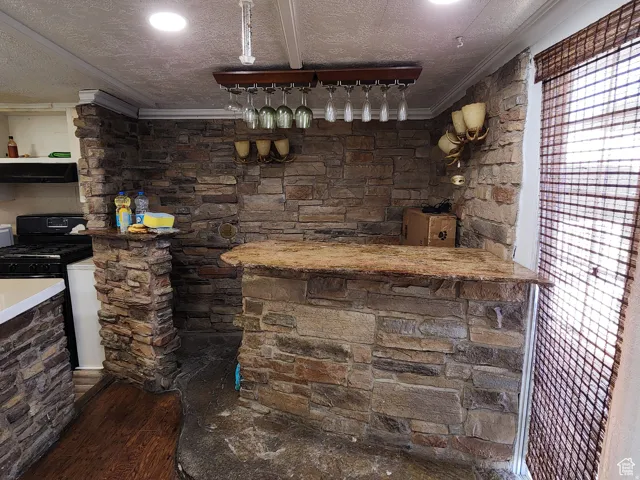 Stone-clad wet bar featuring a natural stone countertop and a built-in wine glass rack