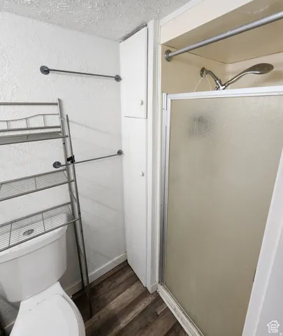 Compact bathroom featuring a walk-in shower with a frosted glass enclosure