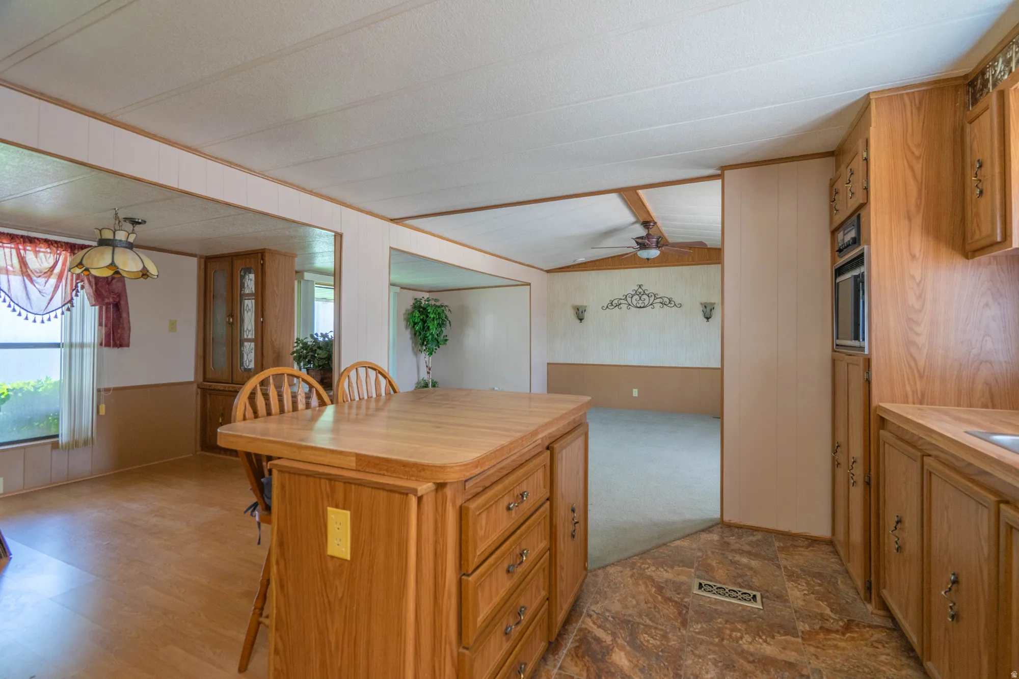 Kitchen island with seating for two, wood-finish cabinetry, built-in microwave, and wood-finish flooring