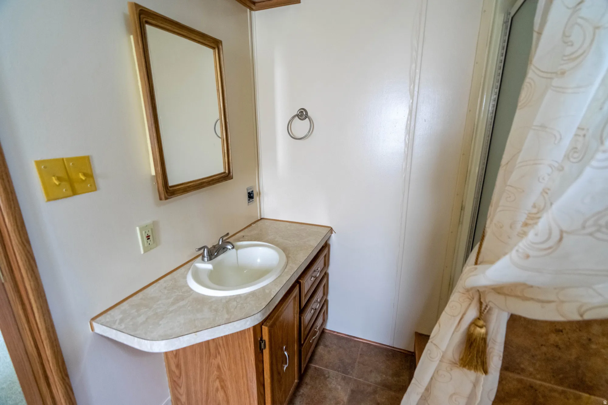 Bathroom vanity featuring a laminate countertop, integrated sink, and wood-finish cabinetry with silver-tone hardware