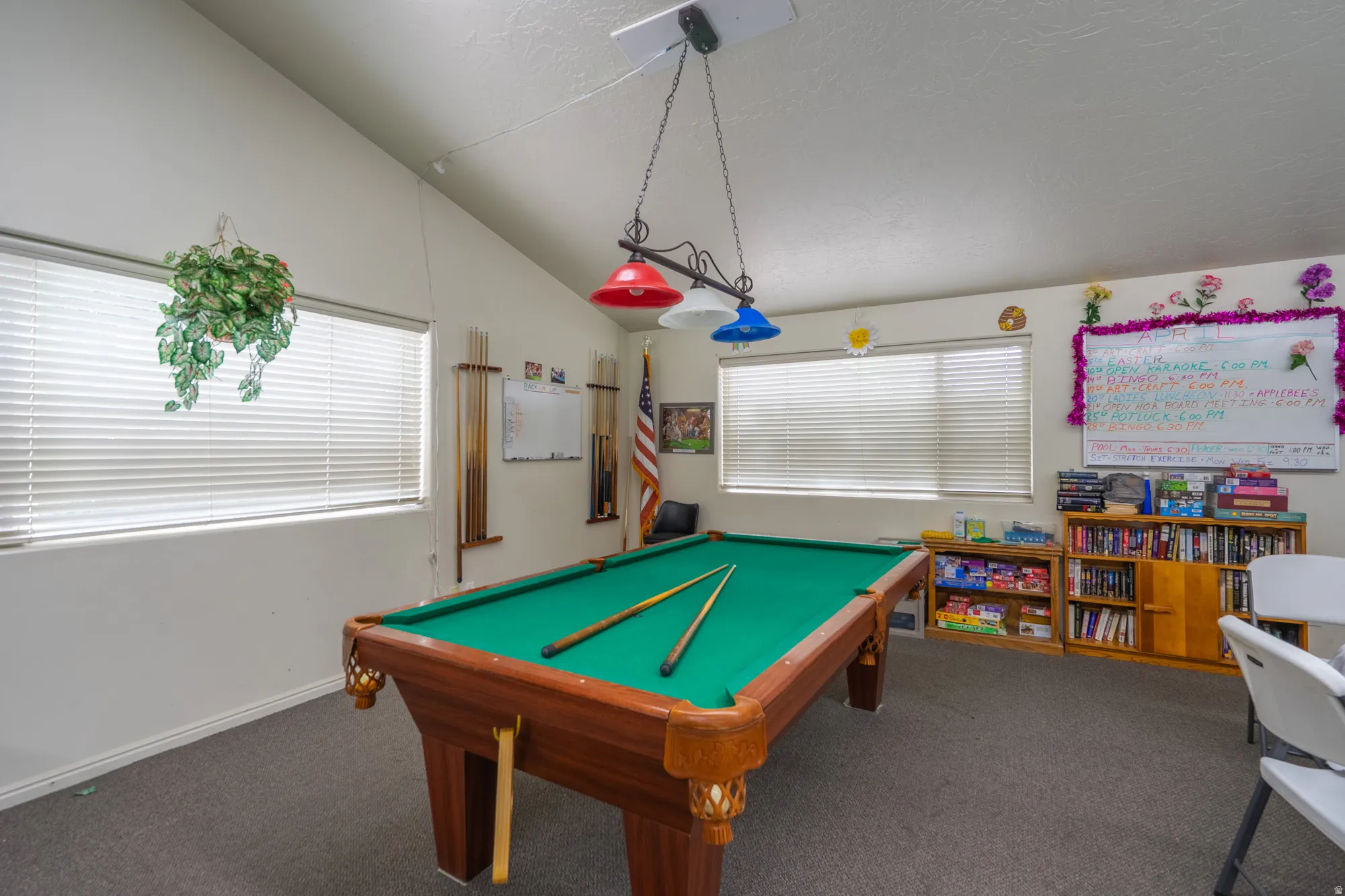 Spacious recreational room featuring a vaulted ceiling and carpet flooring