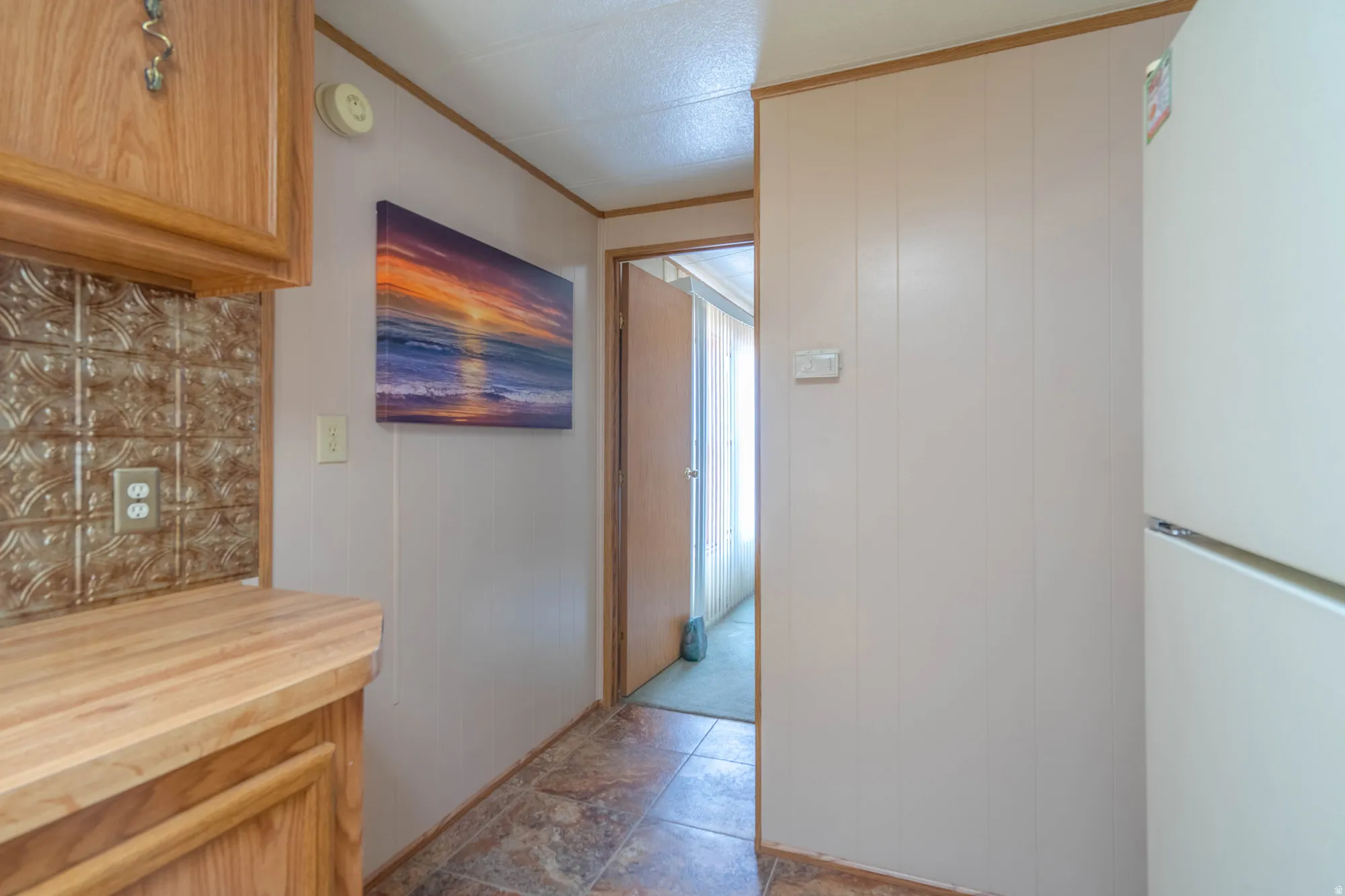 Kitchen area featuring wood cabinetry, a wood-finish countertop, and a decorative tile backsplash