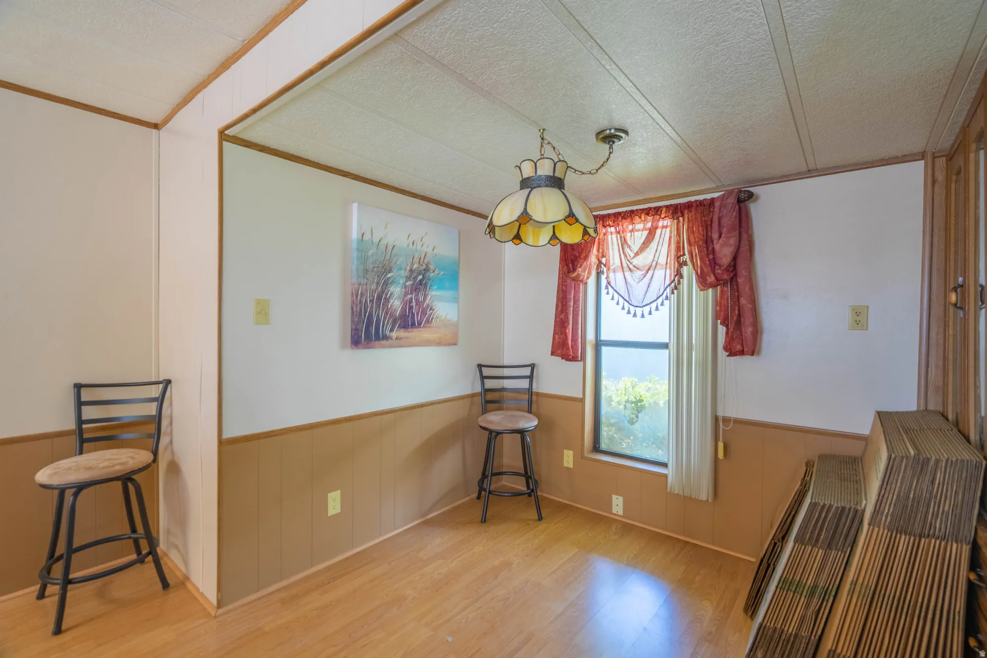 Interior space featuring wood-finish flooring, two-tone wall paneling, and a single window