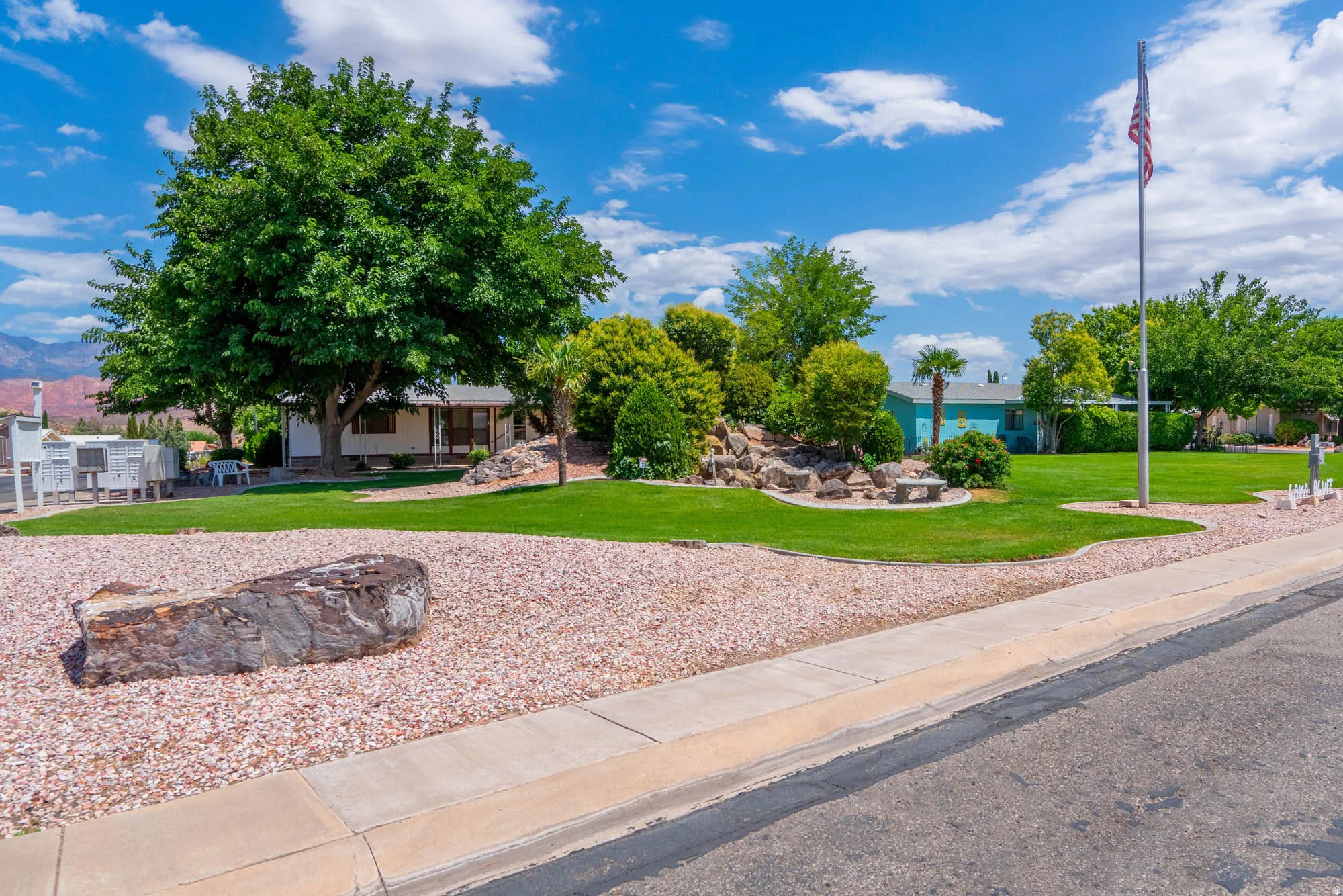 Expansive front yard featuring mature trees, manicured lawn, and decorative rock landscaping