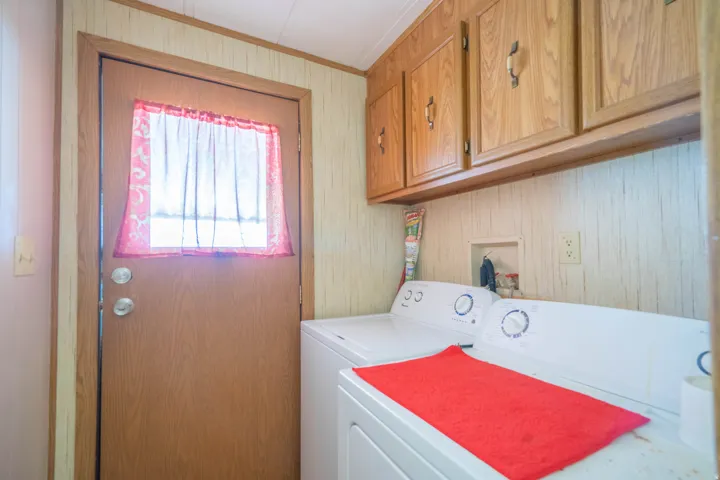 Functional utility space featuring a wood-finish door with an inset window, overhead cabinetry, and paneling accents