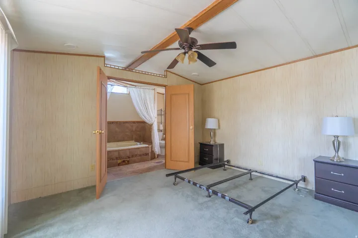 Carpeted bedroom featuring a vaulted ceiling and a ceiling fan
