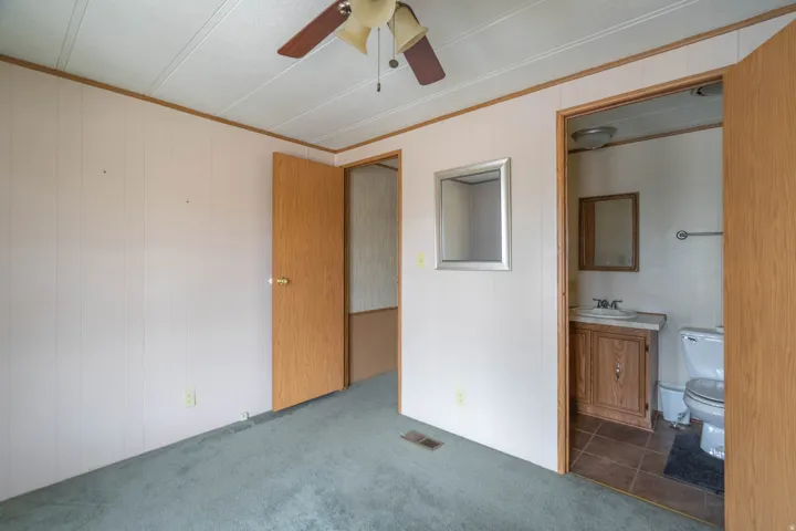 Bedroom featuring a ceiling fan, light wood-finish doors, and soft green carpeting