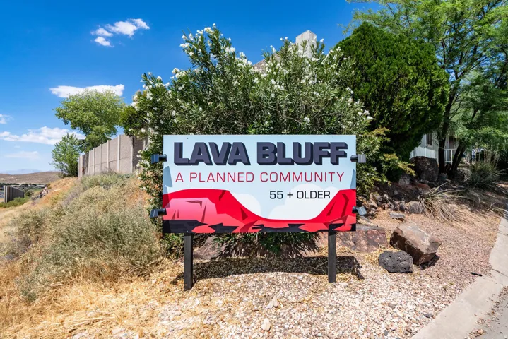 Community entrance sign for Lava Bluff, a planned community, set against natural landscaping with mature shrubs and trees